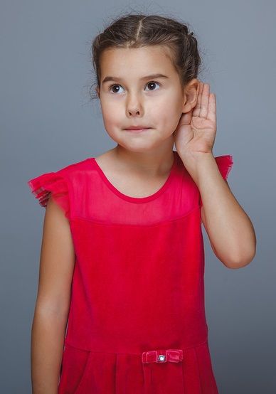 girl holds the hand of a child listening to ear on gray back